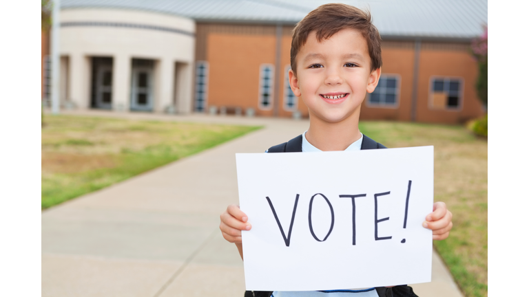 Happy young student at school holding a Vote Sign