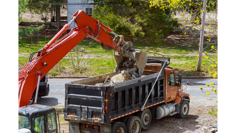 Truck with excavator loading for removal of debris construction waste building demolition