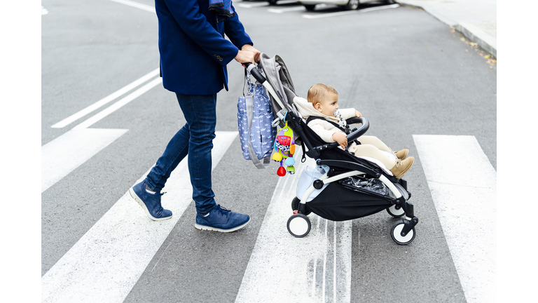 Man with baby stroller crossing road in city