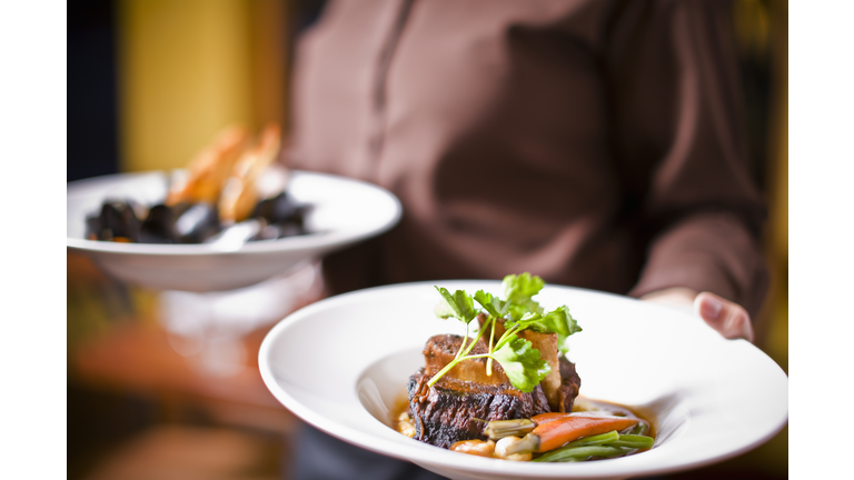 Waitress holding plate of beef tenderloin