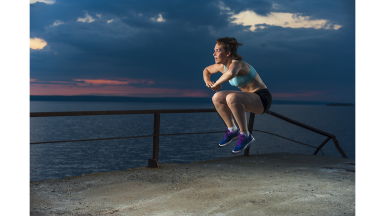 Fit woman doing plyometric exercises on pier