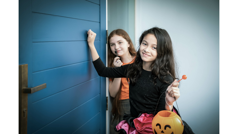 Children boy and girls in Halloween costume dress going trick or treat knocking the door