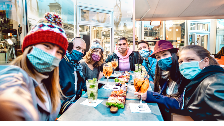 Friends taking selfie outside at cocktail bar - New normal lifestyle concept with young people having fun together at restaurant cafe covered by face masks - Vivid filter with focus on central guy