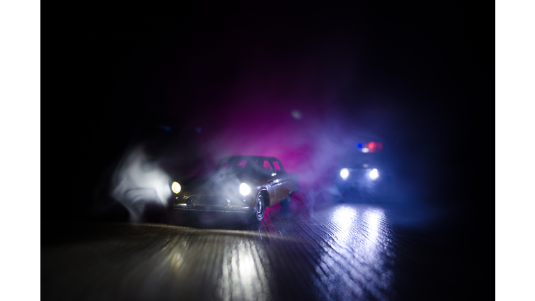 Police car chasing a car at night with fog background. 911 Emergency response police car speeding to scene of crime