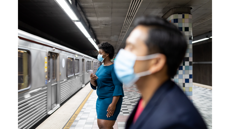 Commuters waiting at subway station with social distance