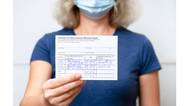 Vaccinated young woman showing COVID-19 Vaccination Record Card