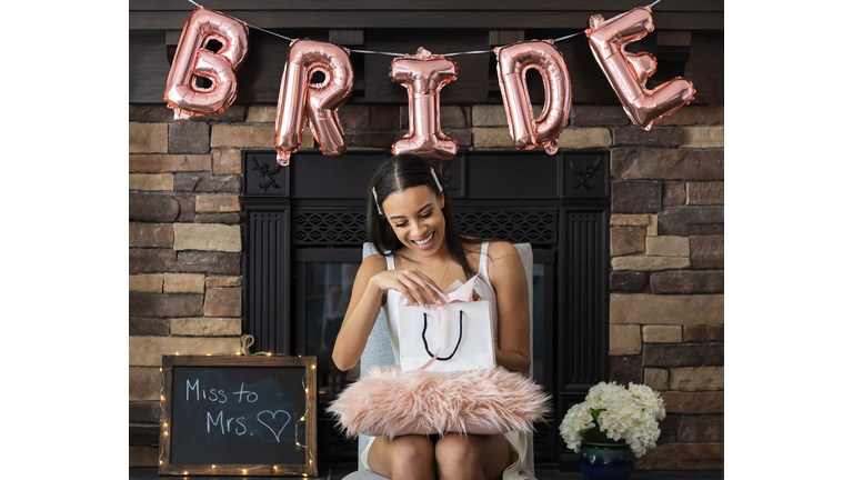 Young beautiful woman opening gift bag at her bridal shower