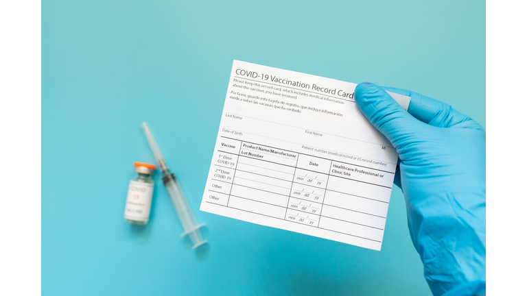 Doctor is holding a vaccination record card and corona virus vaccine vials. Passport of immunity to the coronavirus in the hands of a male doctor. Health passport.