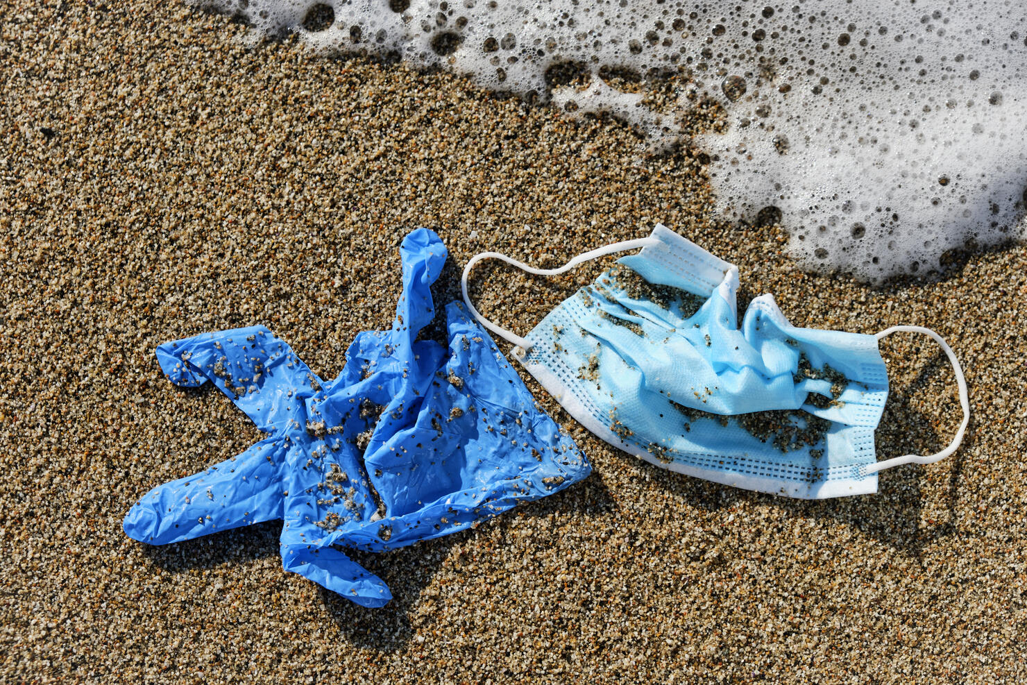 used surgical mask and gloves on the sand