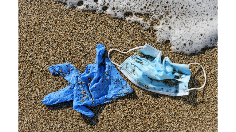 used surgical mask and gloves on the sand