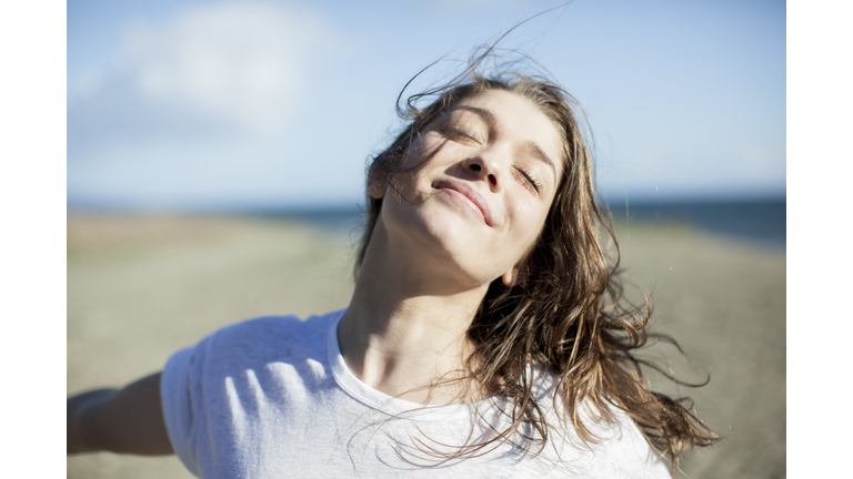 Young woman with eyes closed smiling on a beach