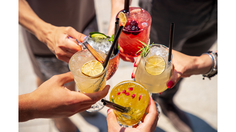 Five cocktails in hands joined in celebratory toast