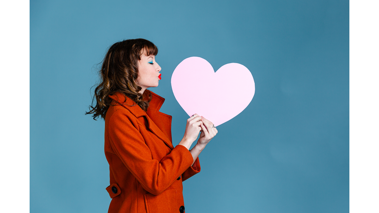 Young woman holding paper pink heart