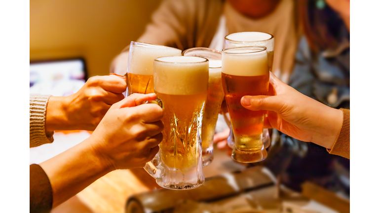 Hands and mug beer of many people toasting at a tavern