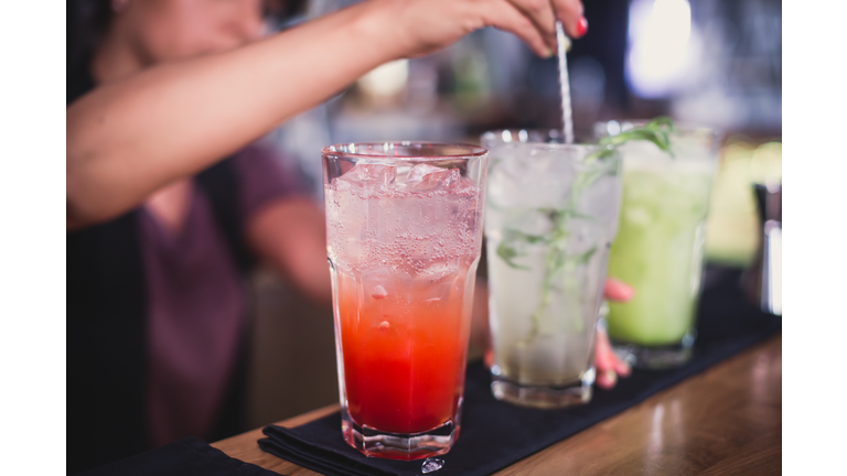 line of different coloured alcohol cocktails on a open-air party