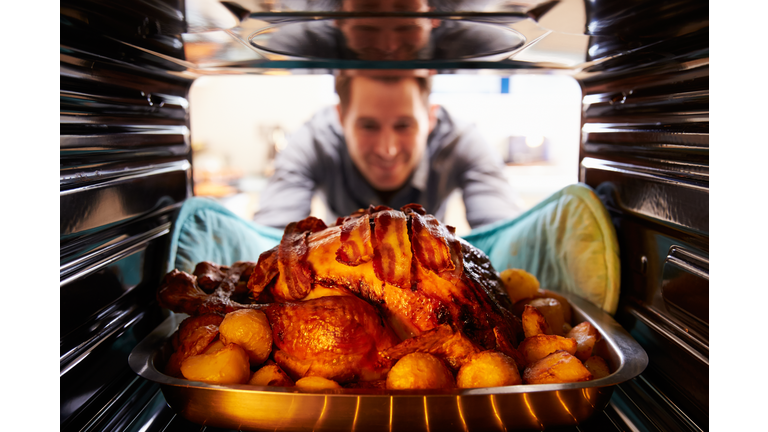 Man Taking Roast Turkey Out Of The Oven