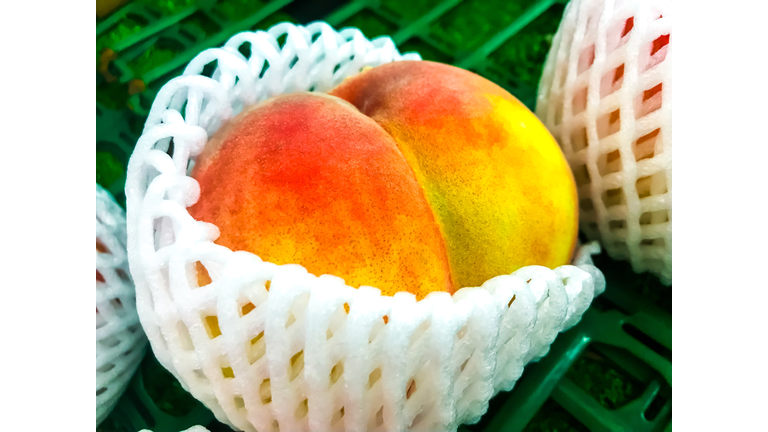 Close-up of a big peach with white plastic mesh cushion