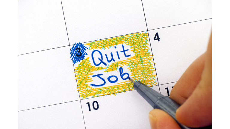Woman fingers with pen writing reminder Quit Job in calendar.