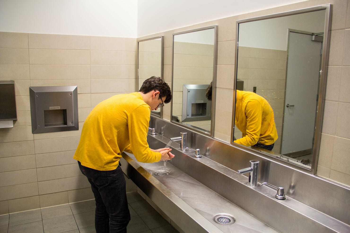 Teen Washing hands in Public Bathroom
