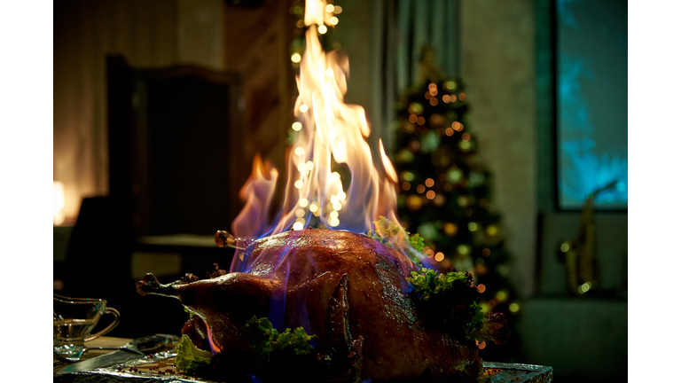 Burning baked turkey on a tray in a dimly lit room.