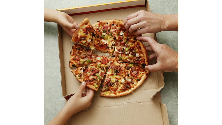 Family taking slices of pizza from pizza box, elevated view