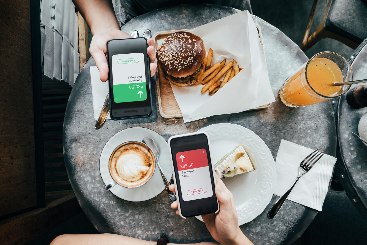 Overhead view of friends sending/receiving the payment of the meal through digital wallet device on smartphone while dining together in a restaurant