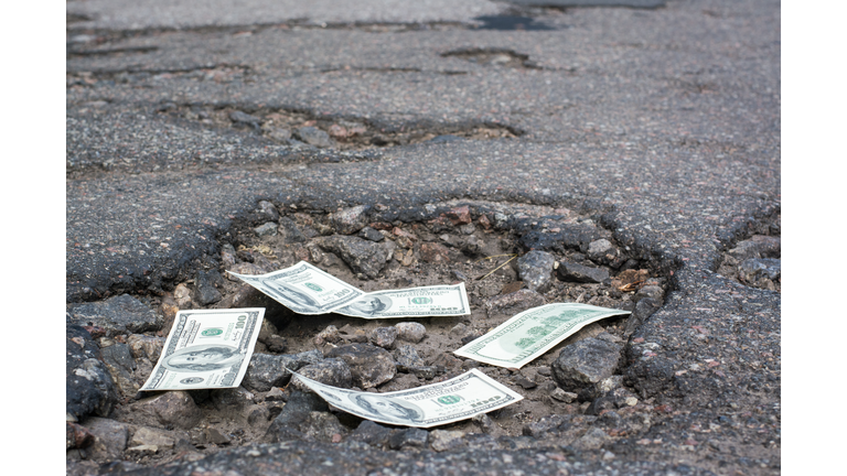 Dollar bills in the potholes on road