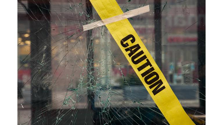 Broken window with glued yellow tape with "CAUTION" lettering