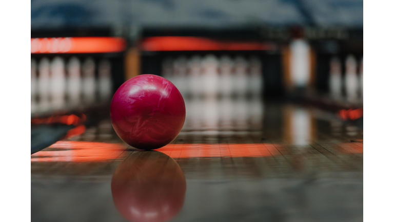 close-up shot of red bowling ball lying on alley under warm light
