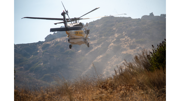 A Los Angeles County Fire Department Firehawk helicopter makes a water drop at a brush fire.