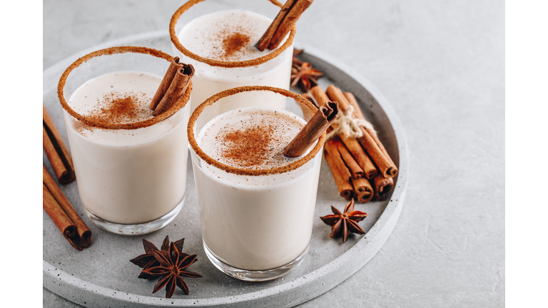 Homemade vanilla Christmas drink Eggnog in glass with grated nutmeg and cinnamon sticks