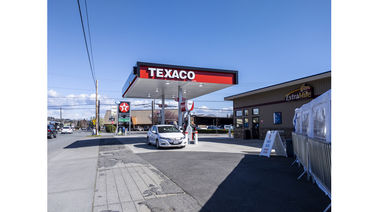 Street view of a small Texaco gas station along the downtown strip on a bright, sunny day.