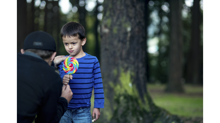 Boy getting offered a piece of candy by a stranger