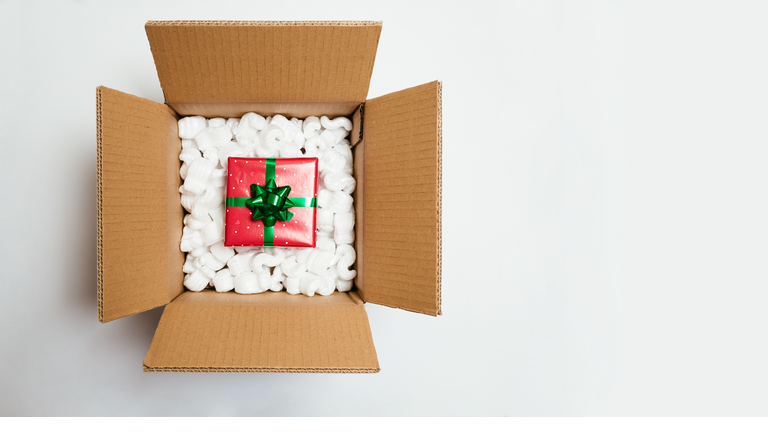 Opened cardboard box with a Christmas gift inside isolated on white