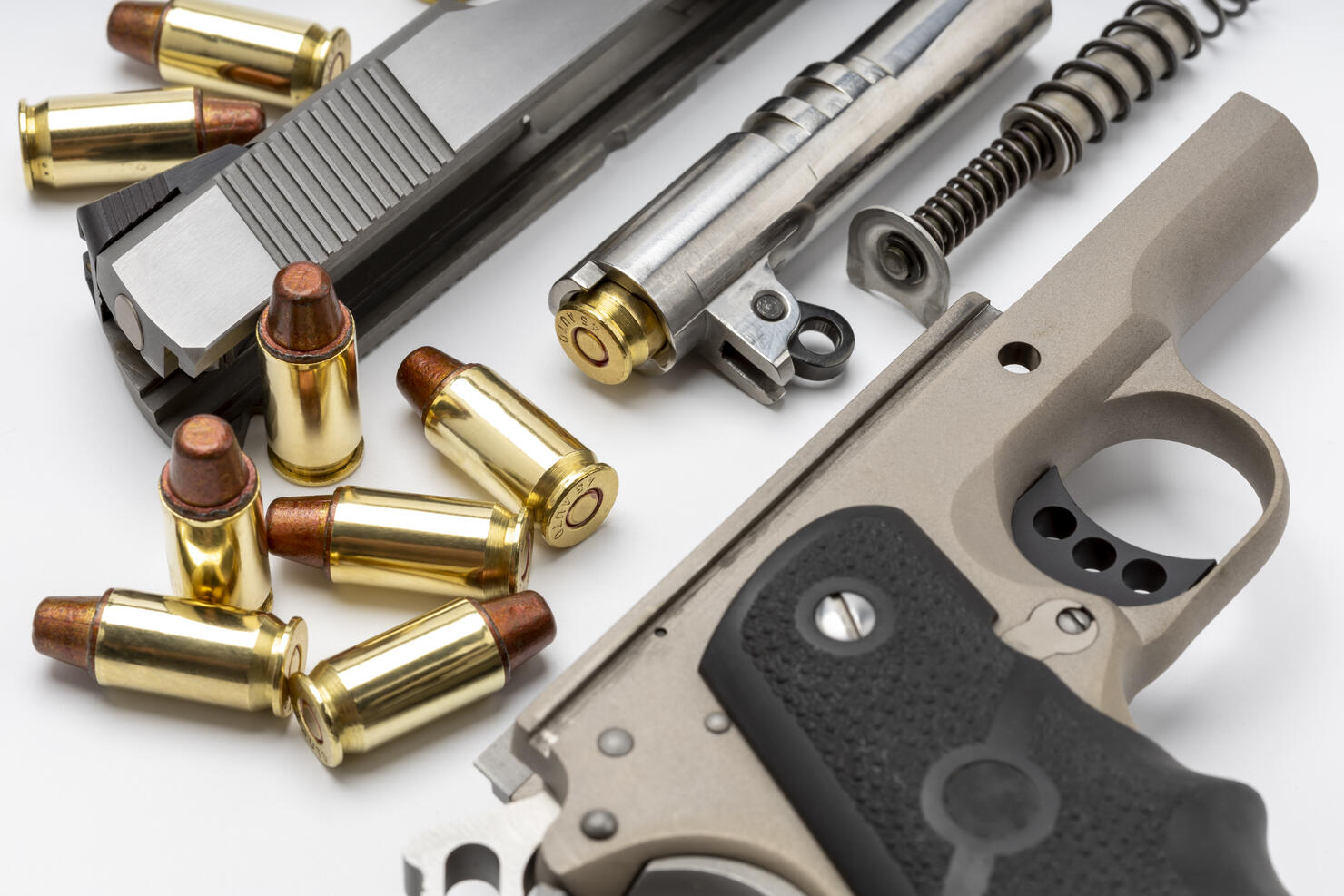 Parts of 1911 gun model and .45 bullets on white background