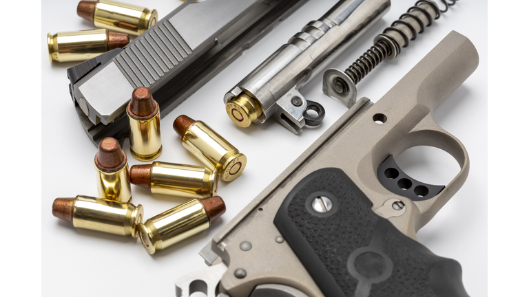 Parts of 1911 gun model and .45 bullets on white background