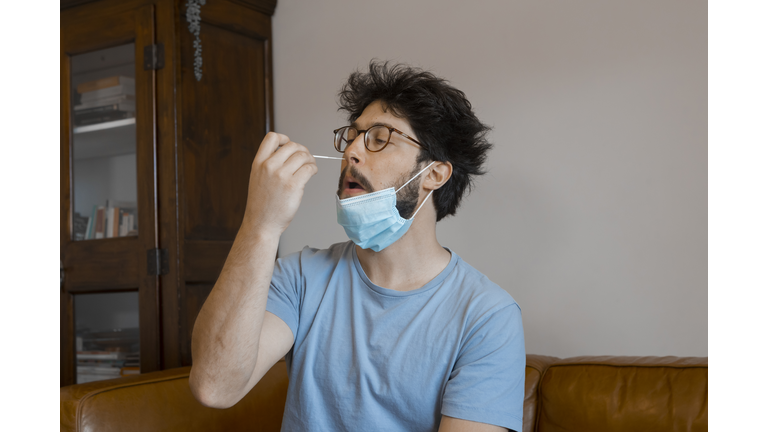 Young man auto checking Coronavirus infection with Antigen kit at home.