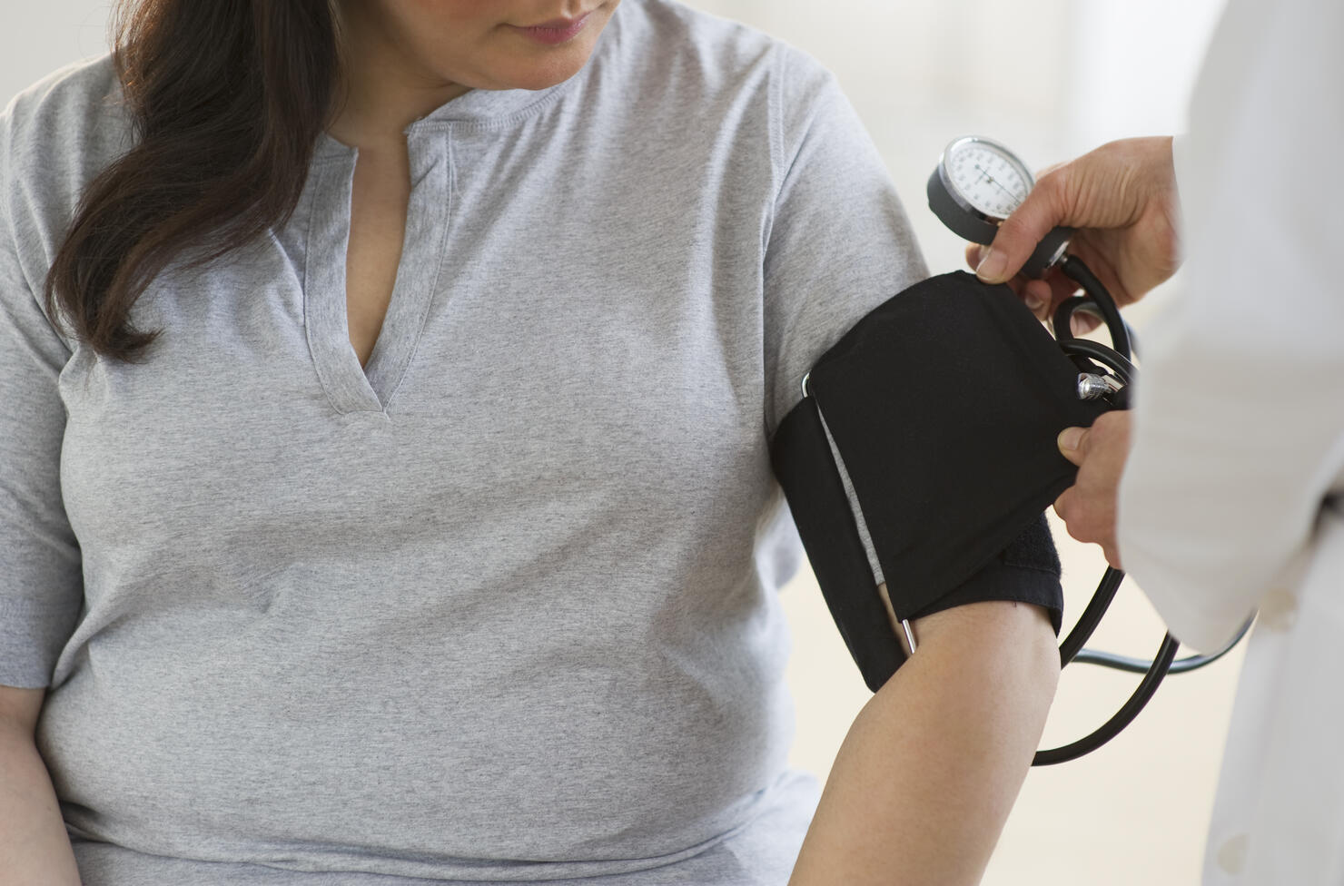 Doctor checking woman's blood pressure