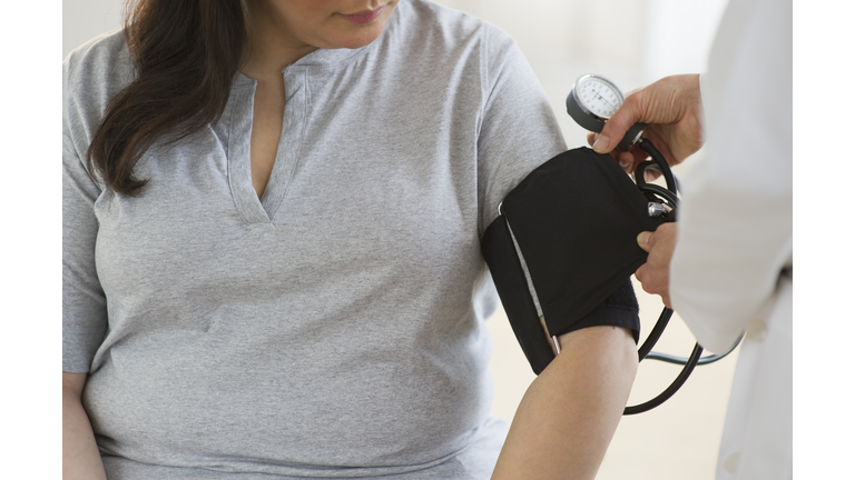Doctor checking woman's blood pressure