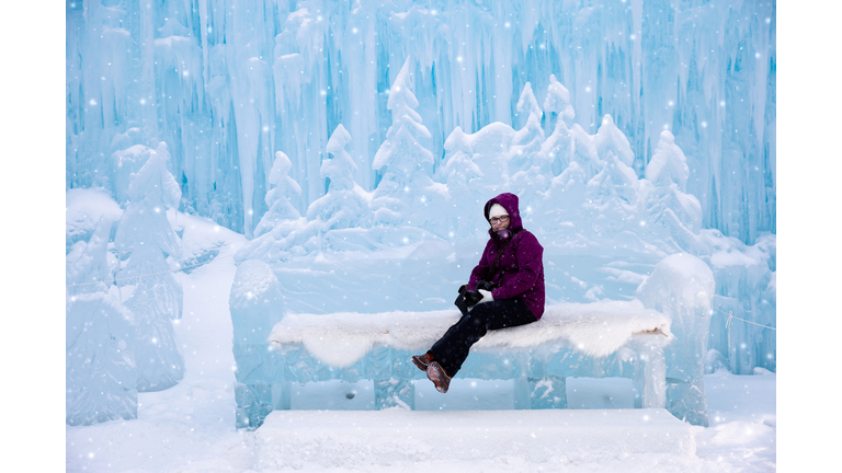 woman sitting on an ice bench at the ice castles