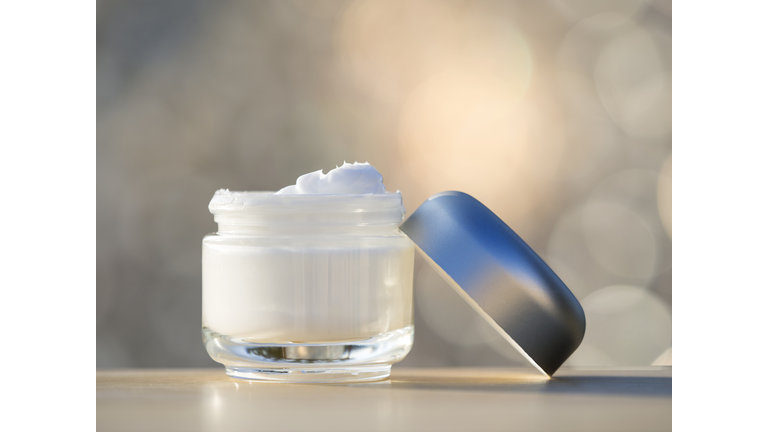 Jar of moisturizing white cream opened,  illuminated with natural light