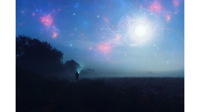 An alien invasion concept. Of glowing UFO's in the night sky with a figure looking up on a misty spooky night.