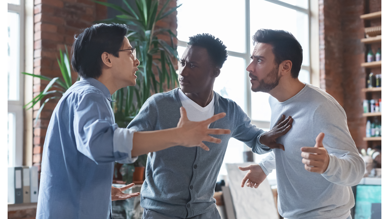 Multiracial coworkers having quarrel in office, conflict of interest