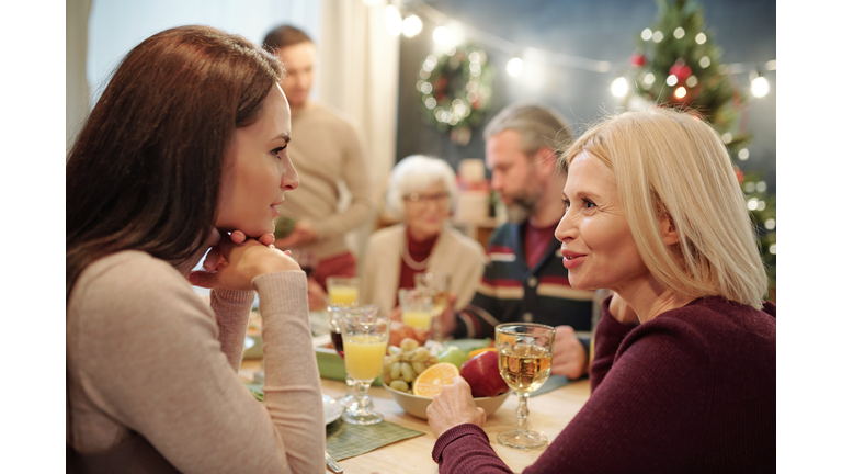 Young and mature women discussing something by served festive table