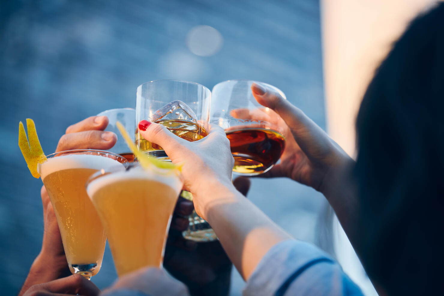 A group of friends makes a toast with drinks in an rooftop