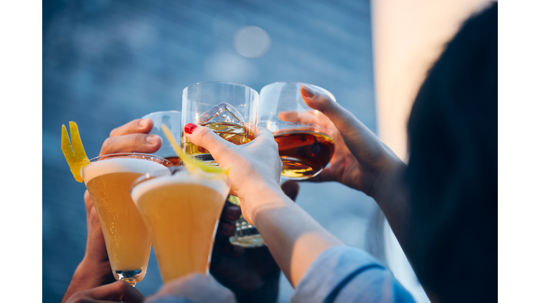 A group of friends makes a toast with drinks in an rooftop