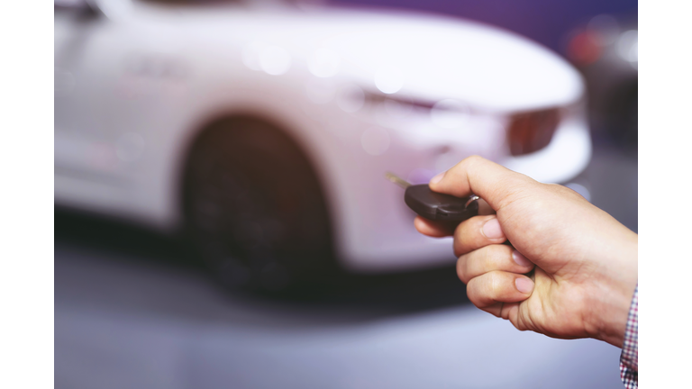 Car key in business man hand. hand presses on the remote control car alarm systems. lock or unlock the door.