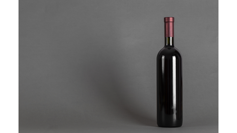 Closed bottle of wine on a grey background. Wine drinking culture concept.