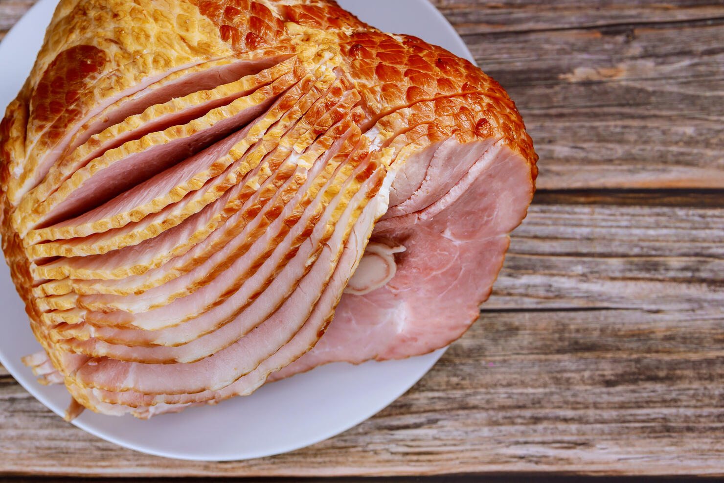 Close up of sliced honey smoked ham on wooden table.