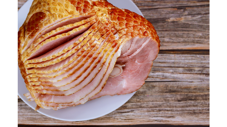 Close up of sliced honey smoked ham on wooden table.